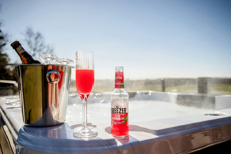 Luxury outdoor hot tub with chilled drinks and champagne glasses under a clear blue sky