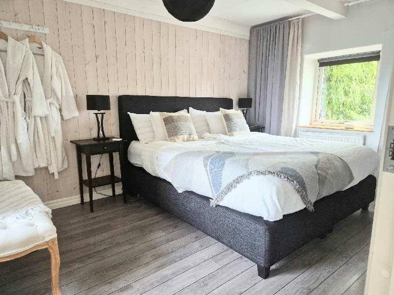 Mysigt sovrum med dubbelsäng, hängande badrockar och fönster mot grönskande natur